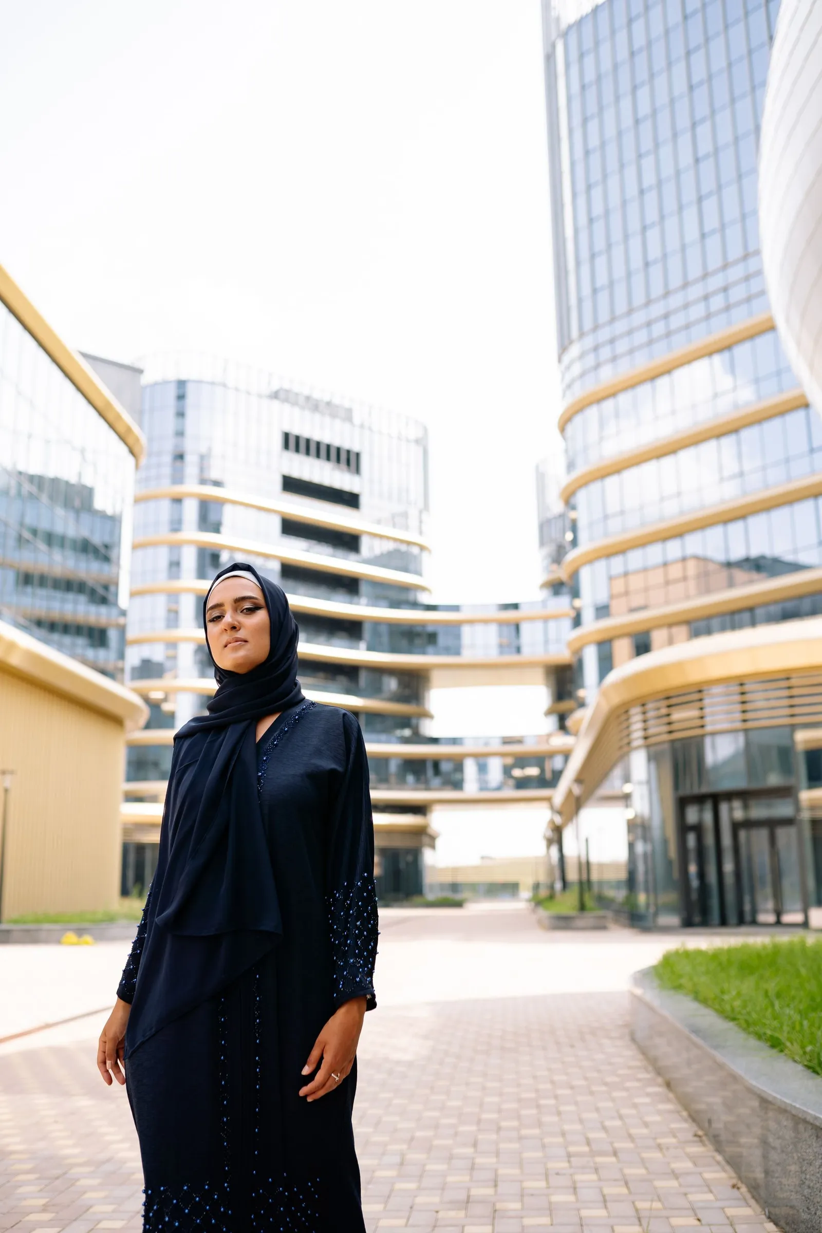 Perempuan berhijab berdiri di antara arsitektur kota modern